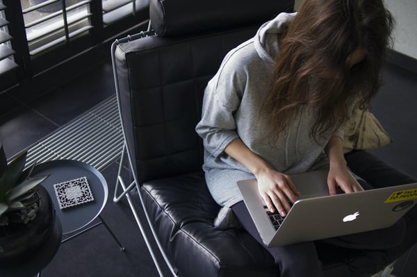 A person with long hair leaning over a laptop computer