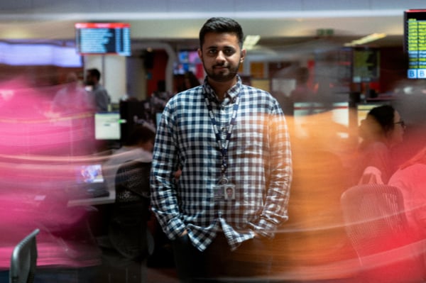 Man in shirt facing forward in busy office